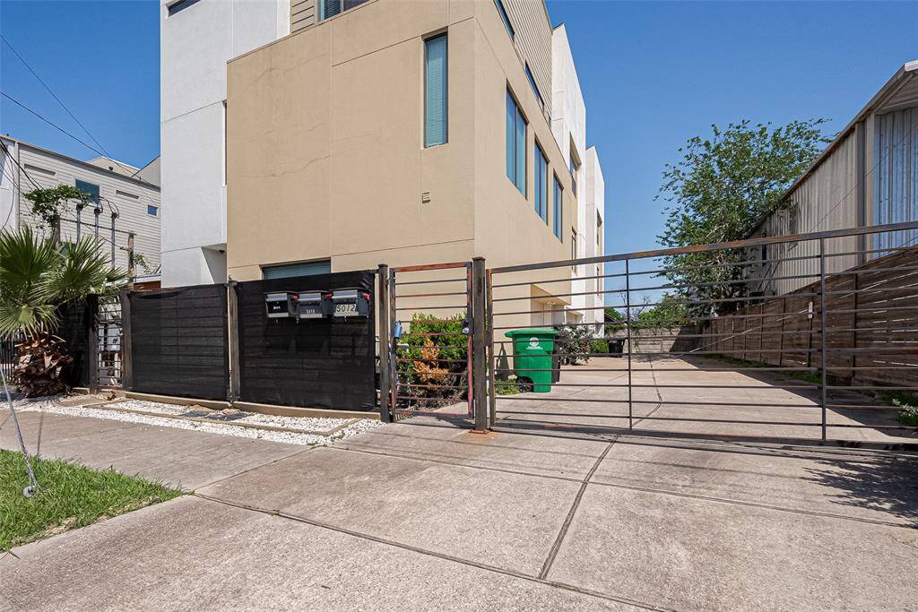 Modern urban property with a gated entrance and driveway, featuring a contemporary building facade. Ideal for privacy and security, with minimal landscaping and a clean, spacious appearance.
