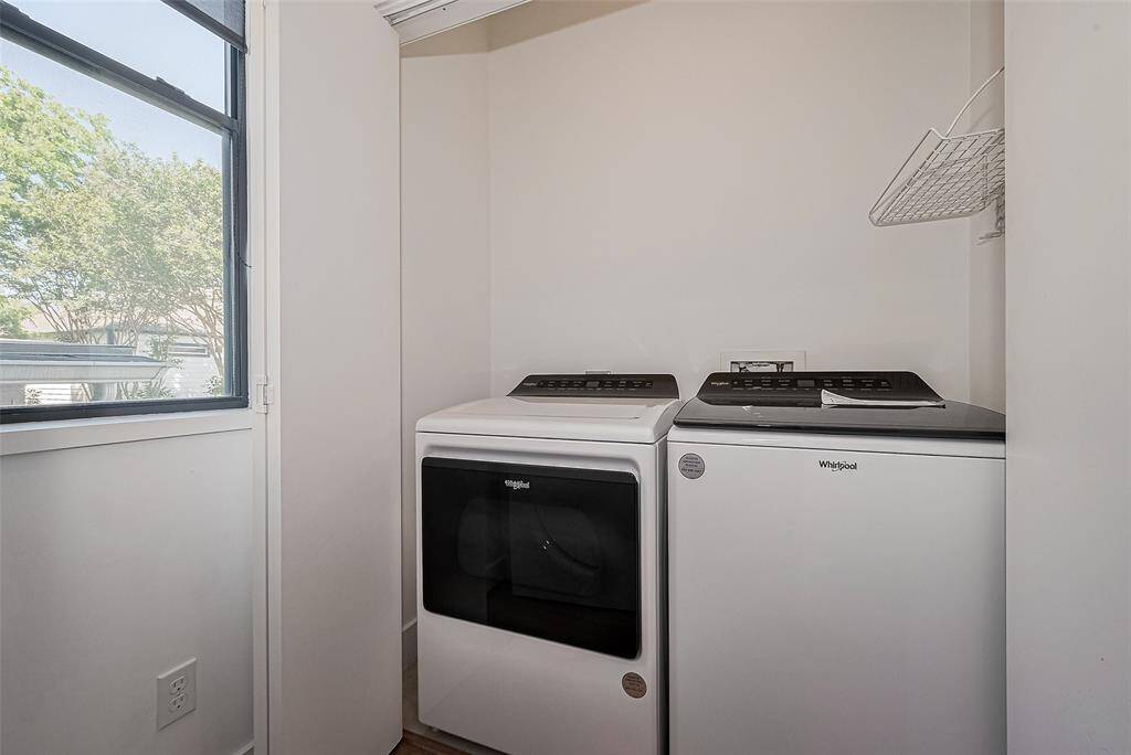 Compact laundry area with a modern washer and dryer, natural light from a window, and a small wall-mounted shelf.