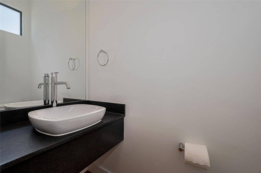 This photo showcases a modern bathroom with a sleek black countertop and a stylish vessel sink. The space is minimalistic with a large mirror and a small window for natural light.