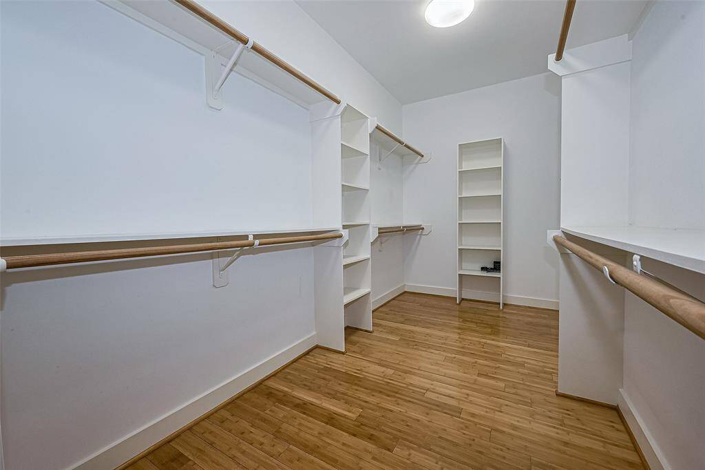This spacious walk-in closet features bamboo flooring, ample shelving, and multiple hanging rods, providing excellent storage and organization potential.
