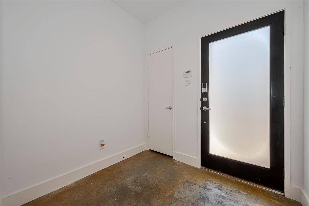 This photo shows a minimalist entryway with a modern frosted glass door, white walls, and a simple, durable floor. It's a clean and functional space that sets a contemporary tone for the home.