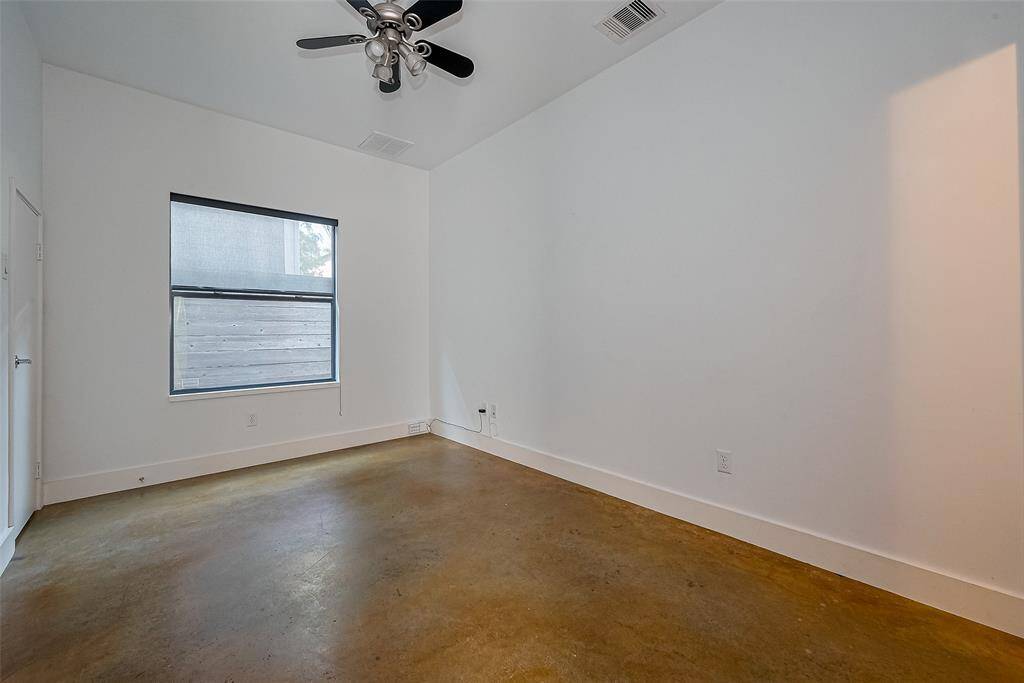 This room features a modern design with white walls and a polished concrete floor. It has a ceiling fan and a window providing natural light. Ideal for a minimalist or contemporary aesthetic.