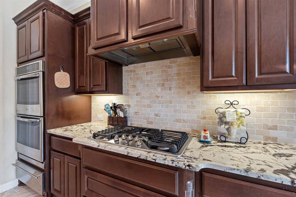 The double oven and 5-burner gas cooktop offer the perfect setup for preparing meals with ease, while the custom backsplash adds a unique touch of elegance and charm. Whether you're cooking for a crowd or enjoying a quiet meal, this kitchen effortlessly combines beauty with practicality.