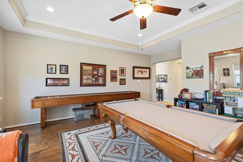 An additional view of the inviting secondary living space which offers a perfect balance of comfort and style, designed for both relaxation and entertainment. The open layout, combined with the elegant tray ceiling and warm wood flooring, enhances the room’s inviting atmosphere. Ample space allows for a variety of uses—whether hosting family and friends, enjoying game nights, or simply unwinding in this versatile area.