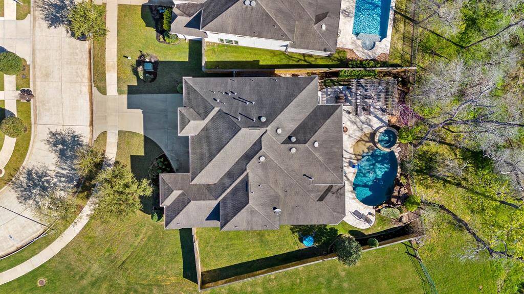Overhead view showcasing the sparkling pool, attached spa, and built-in fireplace. The oversized corner lot provides ample space and privacy, with a double-wide driveway adding grandeur and convenience.
