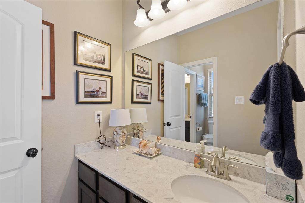 Well-appointed Jack and Jill bathroom with sleek countertops, an oversized mirror, and warm cabinetry. A bright, airy space with ample storage that combines style and practicality.