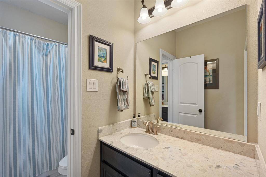 Well-designed Jack and Jill bathroom featuring an extended countertop, upgraded lighting, and warm cabinetry, creating a stylish and functional space.