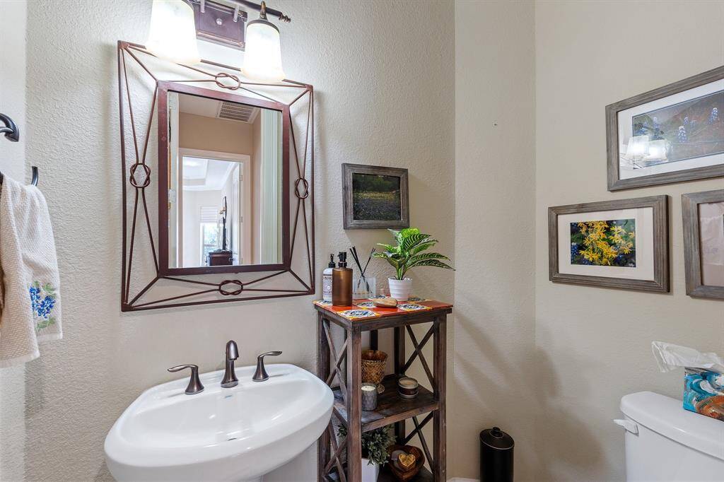 Stylish powder room on the main floor features a unique mirror that adds a touch of character and sophistication to the space. Upgraded lighting enhances the room's ambiance, creating a warm and inviting atmosphere.