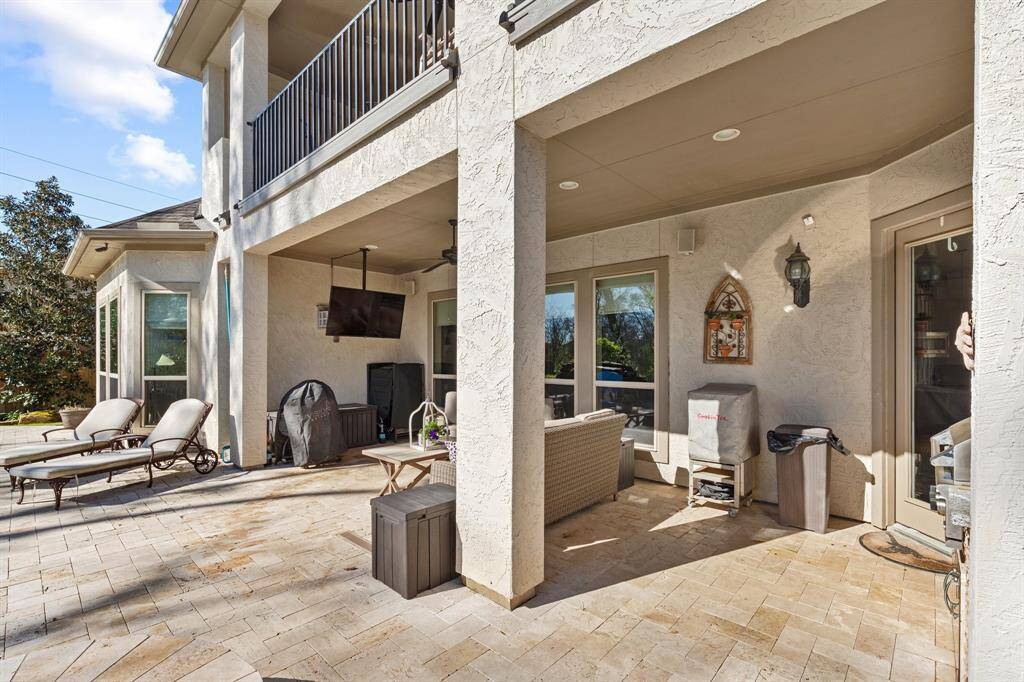 Beautiful outdoor living area designed for both relaxation and entertainment, featuring a cozy sitting area perfect for unwinding. The space includes a TV for enjoying your favorite shows or sports while outdoors, and a built-in grill ideal for cooking and hosting gatherings.