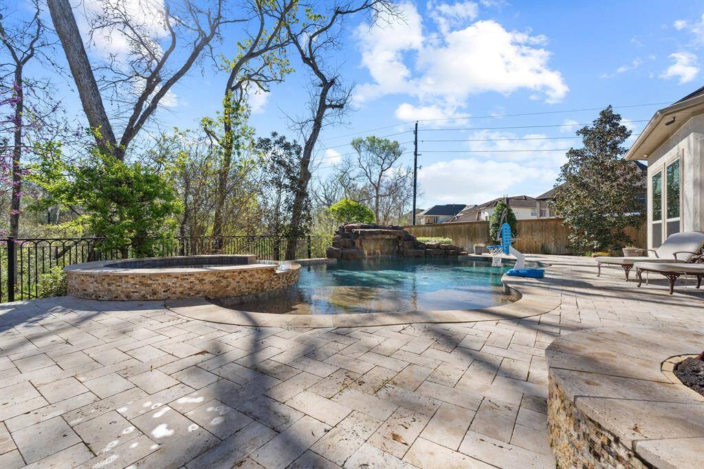 This stunning pool and spa area is a true outdoor paradise, featuring a relaxing waterfall that adds both beauty and soothing sounds to the space. Surrounded by lush, wooded landscaping, it offers the perfect blend of privacy and tranquility.