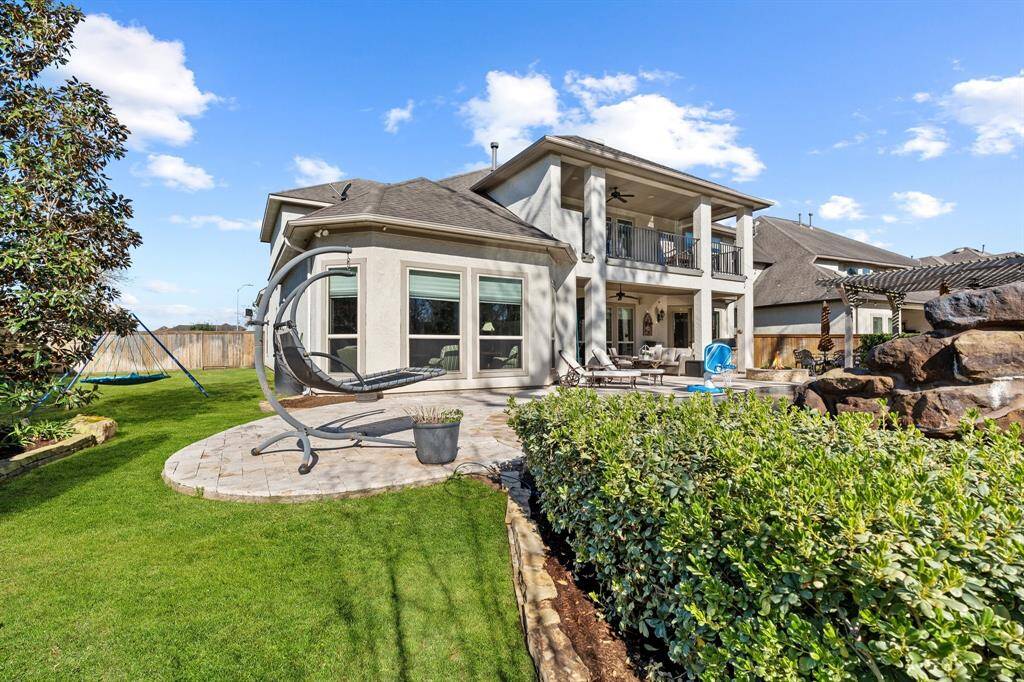 This breathtaking exterior shot captures the beauty of the back of the home, featuring a spacious balcony overlooking the serene pool and inviting outdoor living area. The well-designed layout seamlessly blends indoor and outdoor spaces, offering the perfect setting for relaxation and entertainment.