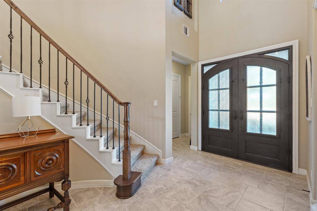 A custom arched front door leads to a striking spiral staircase with a wrought iron railing, establishing a luxurious tone as you enter the home.