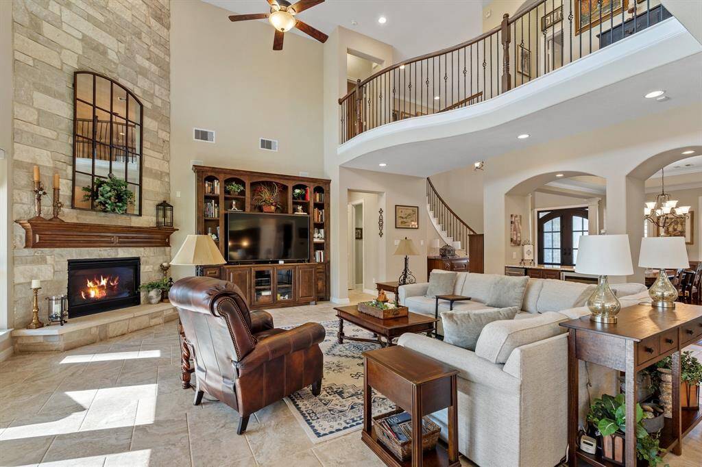 This spacious living room seamlessly connects with the entryway, dining room, and gourmet kitchen, creating an open, airy floor plan ideal for entertaining. The upstairs balcony adds an elegant touch to the overall design.