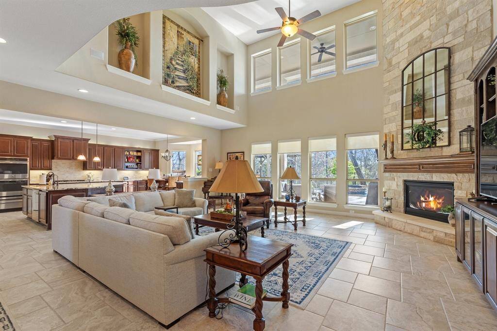 A WALL OF WINDOWS offers a seamless view of the pool and outdoor living area. A floor-to-ceiling stone fireplace serves as the focal point, while built-in shelving adds style and function.