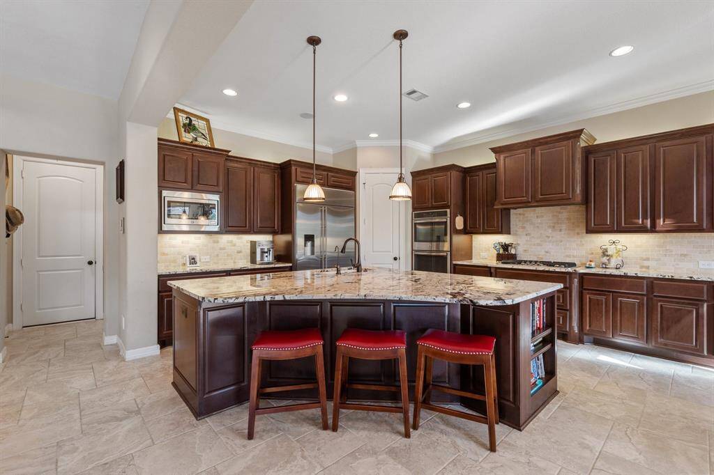 The gourmet kitchen features a spacious island with breakfast bar and pendant lighting, perfect for meal prep or casual dining. Sleek granite countertops offer both elegance and practicality.