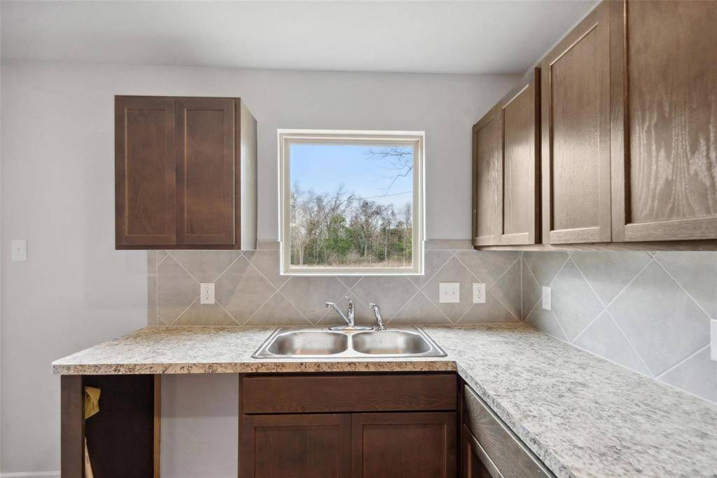 The kitchen features recessed lighting, a large window that overlooks the backyard, with the back door opening up the stunning outdoor space!