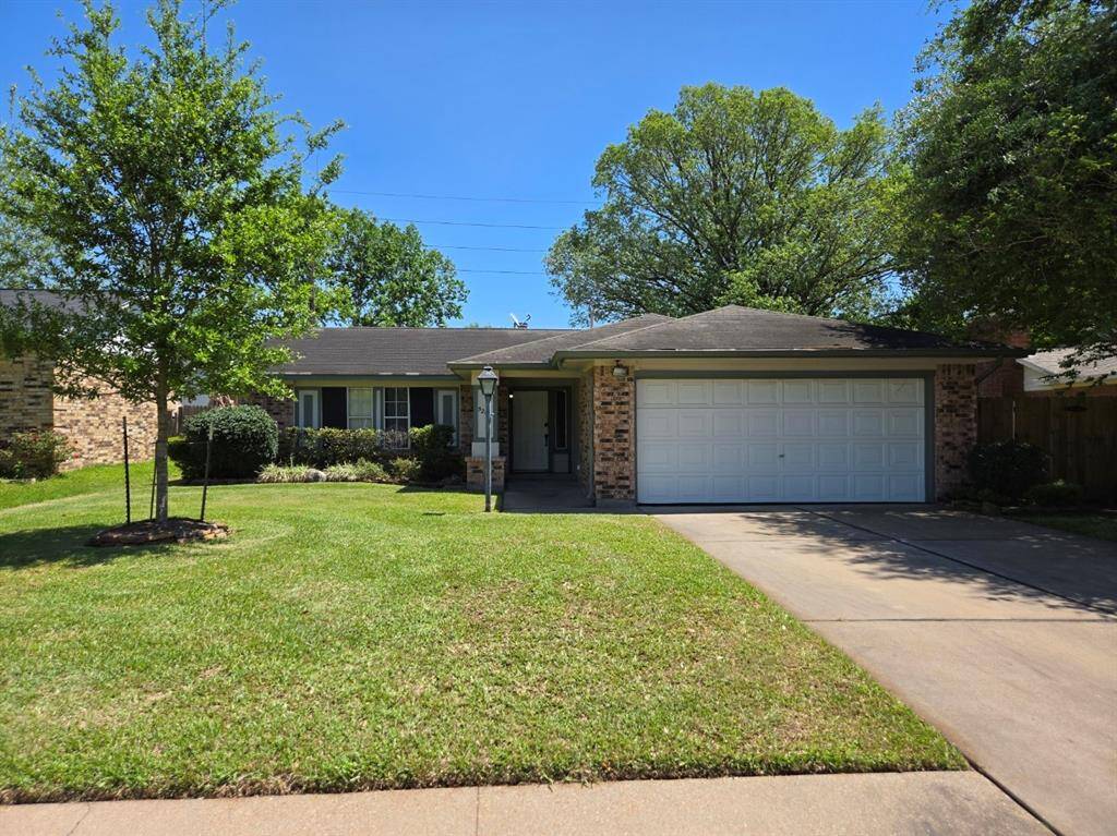Charming single-story home with a well-maintained front yard, mature trees, and a two-car garage. The exterior features brick details and a welcoming entryway.