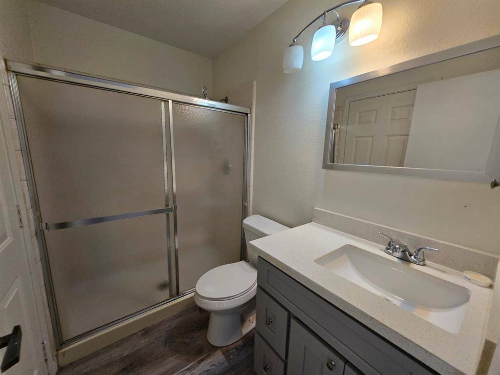 This bathroom features a modern design with a glass-enclosed shower, sleek vanity with a white countertop, and contemporary lighting fixtures, offering a clean and functional space.