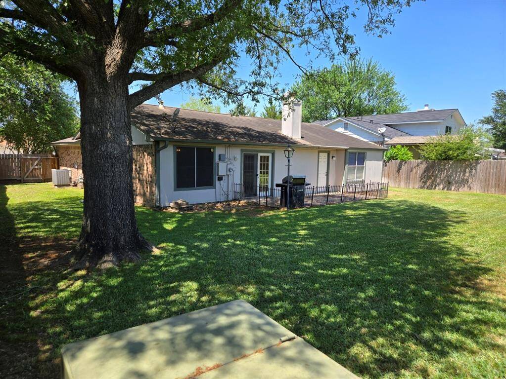 Charming backyard with a spacious lawn, mature trees providing shade, and a cozy patio area. Perfect for outdoor relaxation and entertaining.