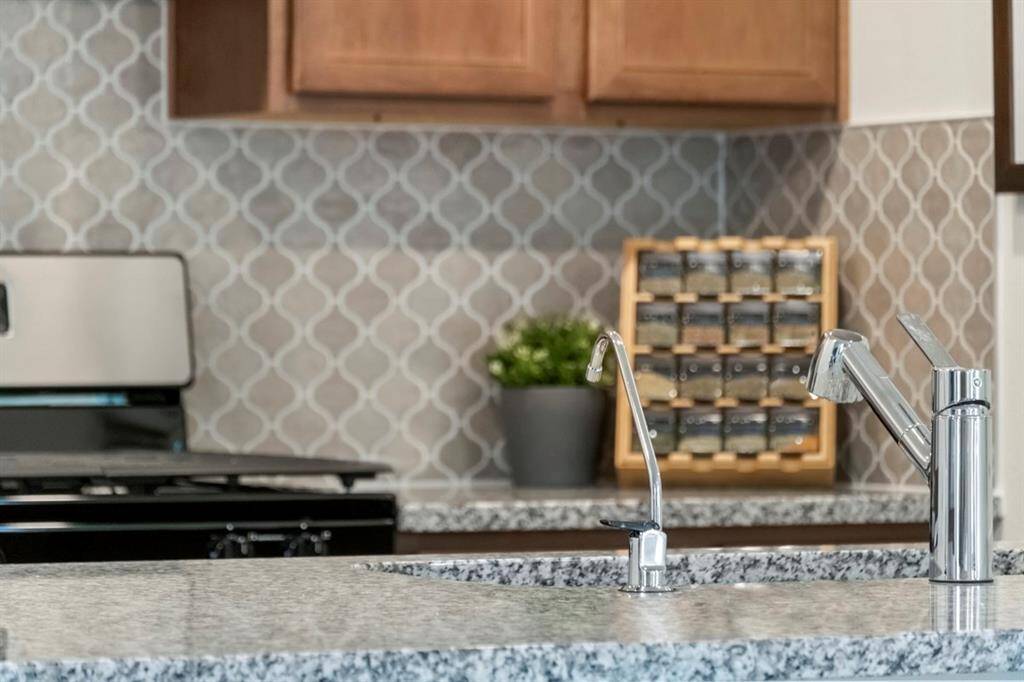 The kitchen solid surface countertop featured here is Granite color in Luna Pearl and gorgeous mosaic tile backsplash.
