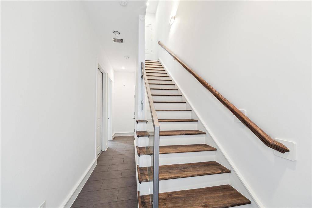 Welcoming entry-way with new flooring and hardwood stairs leading to the living room.