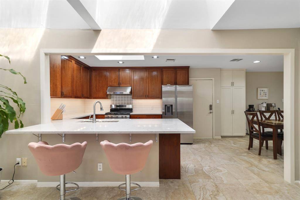 A Quartz Topped Breakfast Bar offers Convenient Seating for 4 between the Well Designed Kitchen and the Family Room.  The Kitchen also features a Samsung Stainless Steel Side by Side Refrigerator (Remains per Seller) 2021*, Staggered Stone Style Porcelain Tile Floors and Sherwin Williams "Beach" Designer Paint* (*per Seller).