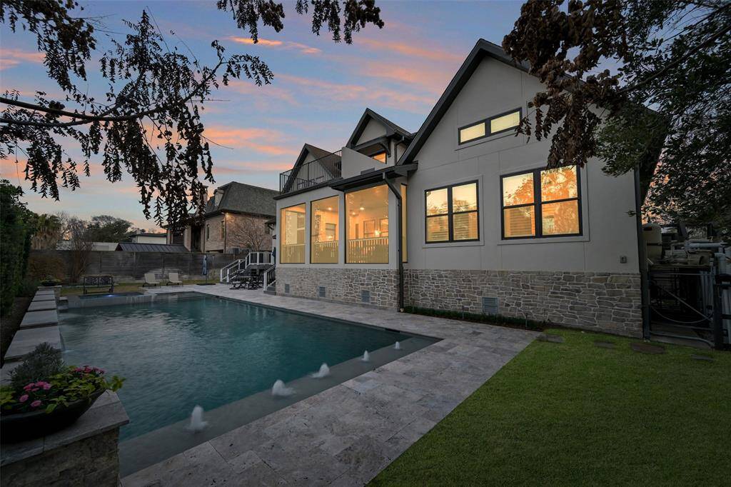 This view is from the opposite side of the yard showing the game room to the right just off the screened porch and on the far end of the home are the stairs from the primary suite patio.