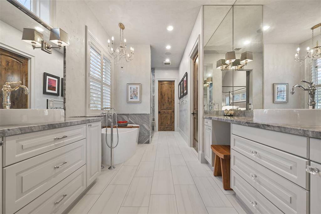 Luxuriously appointed primary bath with marble countertops walk-in shower and vessel tub. note the double sinks and vanity space.