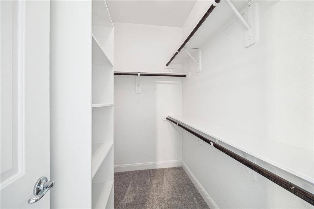 Walk in closet in the primary bedroom with built in shelves.