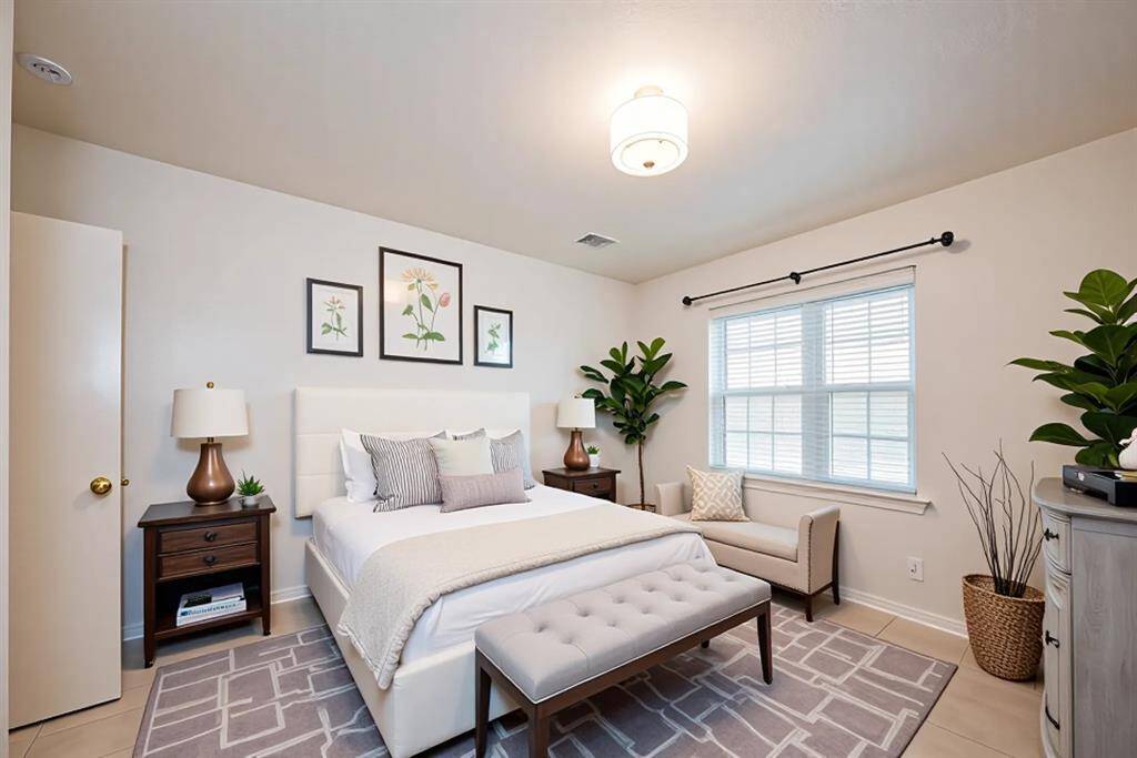 This virtually staged third bedroom is a calm, sun-filled retreat featuring soft neutral walls, modern lighting, and stylish tile flooring. The layout easily accommodates a bed, seating area, and nightstands—making it perfect as a guest suite, peaceful escape, or flexible bonus room. Thoughtfully styled to show off its full potential.