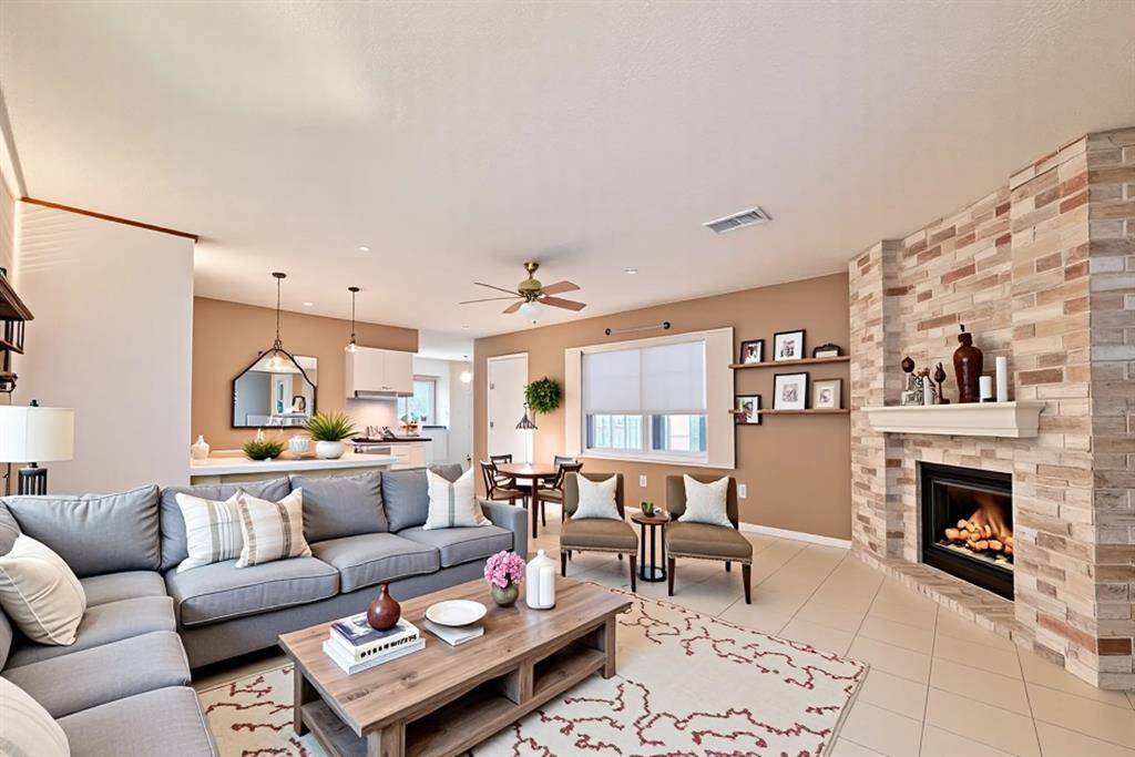 This spacious family room (virtually staged) is the heart of the home—offering an open-concept layout, cozy gas fireplace with floor-to-ceiling brick, and seamless flow into the kitchen and dining areas. With neutral tile flooring, designer lighting, and plenty of natural light, it’s the perfect space to gather, relax, and entertain with ease.