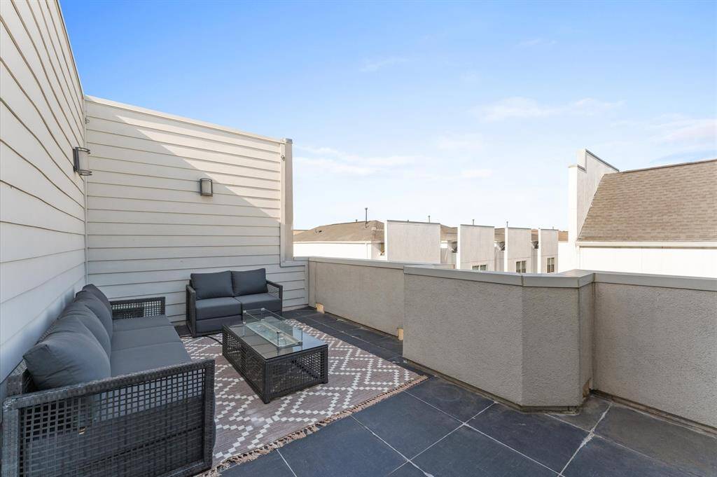 Expansive private rooftop deck with outdoor seating, sconces lighting, and a fireplace—perfect for entertaining or relaxing under the stars.