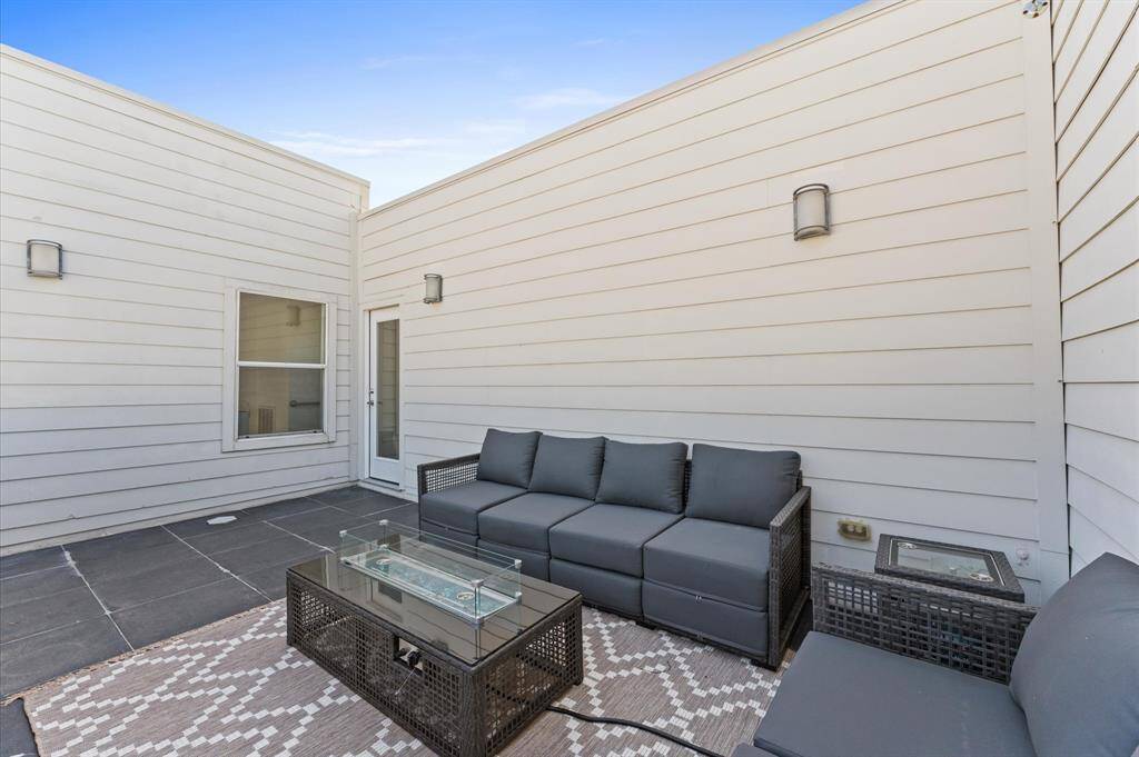 Expansive private rooftop deck with outdoor seating, sconces lighting, and a fireplace—perfect for entertaining or relaxing under the stars.
