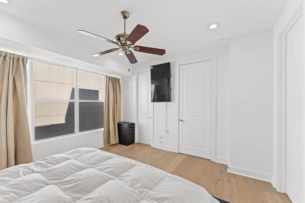 Spacious and serene primary suite with large windows, king-sized bed, walk-in closet, and stylish accents for comfort and rest.