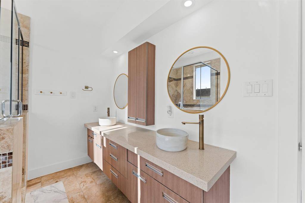 Spa-inspired primary bath with a soaking tub, separate glass-enclosed shower, dual vanities, and tasteful tile work.