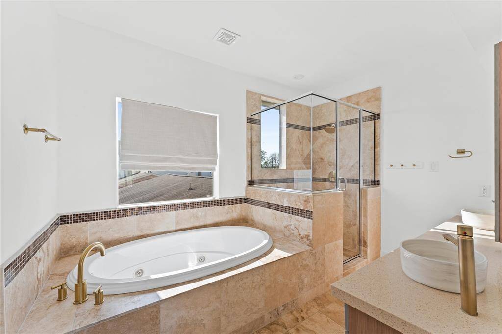 Spa-inspired primary bath with a soaking tub, separate glass-enclosed shower, dual vanities, and tasteful tile work.
