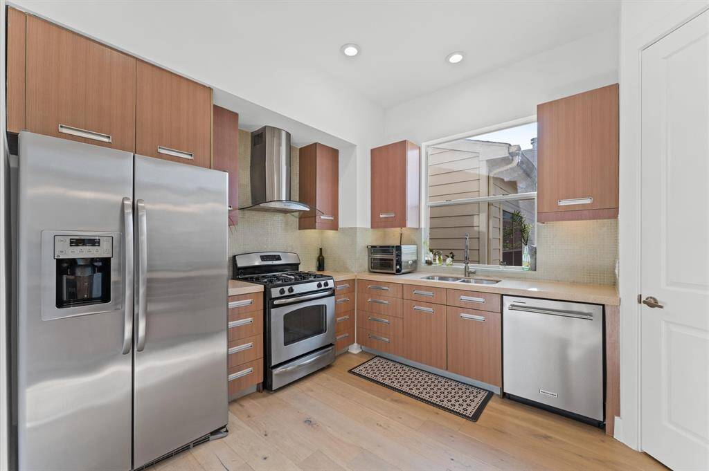 Fully equipped kitchen featuring stainless steel appliances, ample cabinet space, quartz counters, and a functional island perfect for meal prep or morning coffee.