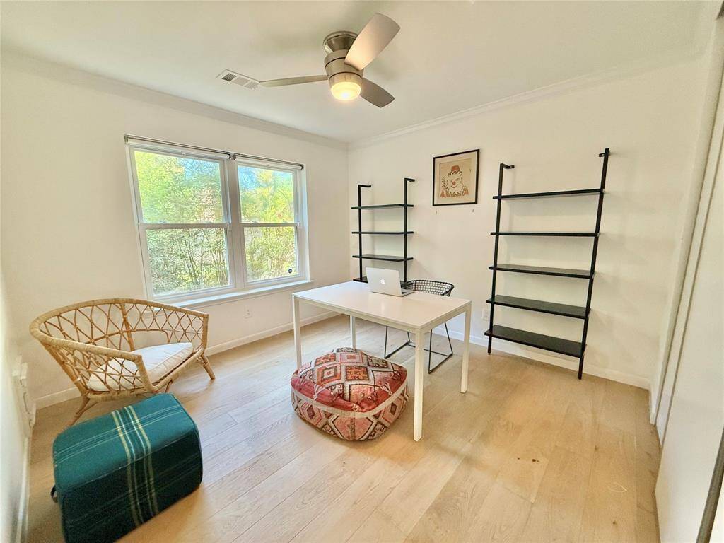 Bright and airy home office with large windows, light wood flooring, and modern ceiling fan.