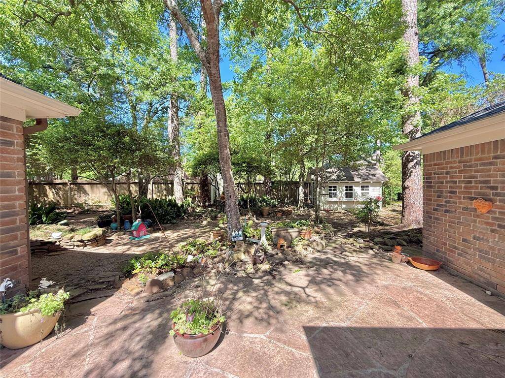 Charming backyard with mature trees providing shade, a paved patio area, and a cozy shed. Ideal for relaxing or gardening, with ample space for outdoor activities.