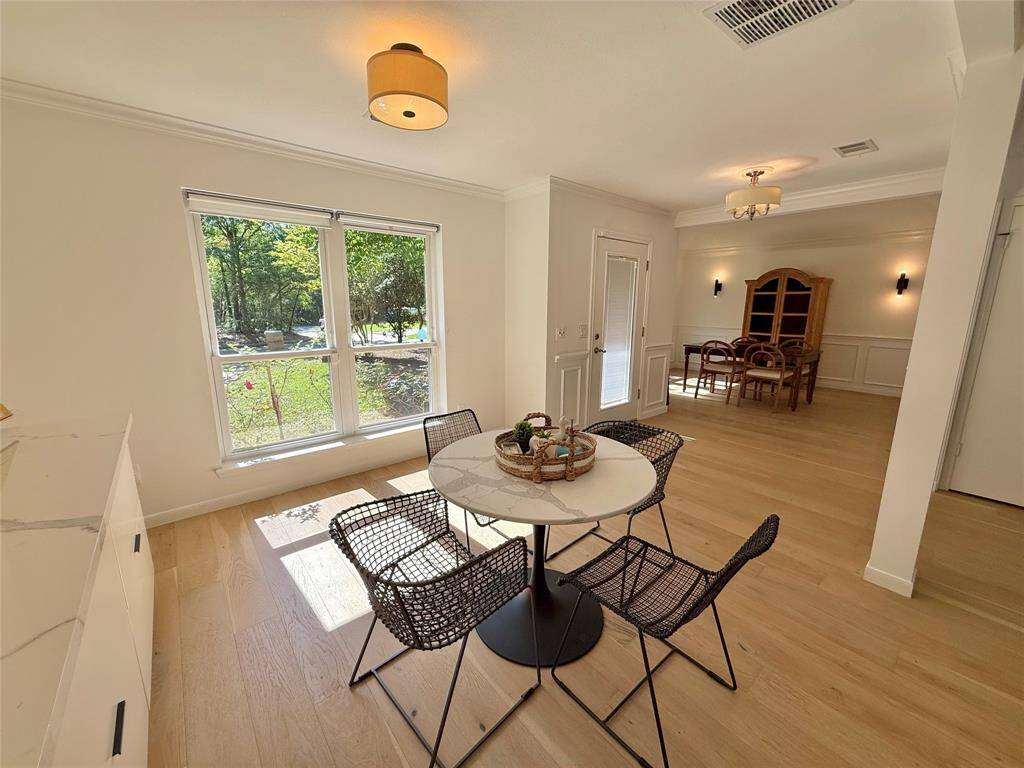 Bright dining area with large windows, wood flooring, and modern lighting. Features a cozy breakfast nook and a separate formal dining space. Natural light enhances the open and inviting atmosphere.
