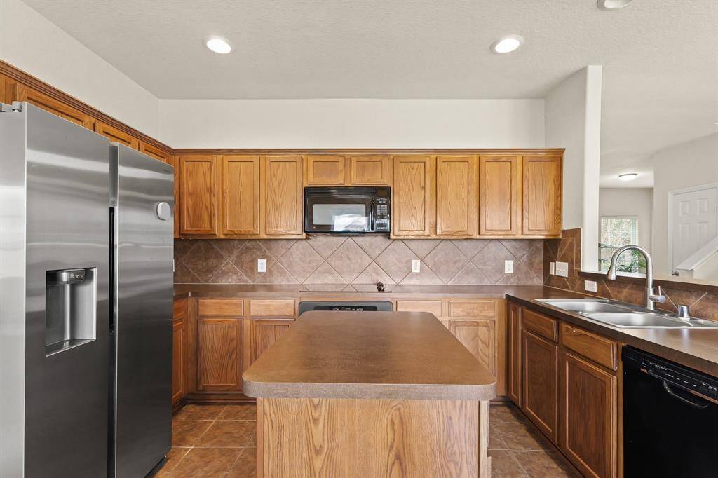 The kitchen is fully equipped with stainless steel appliances, tile floors, recessed lighting, a kitchen island, plenty of cabinetry and counter space.