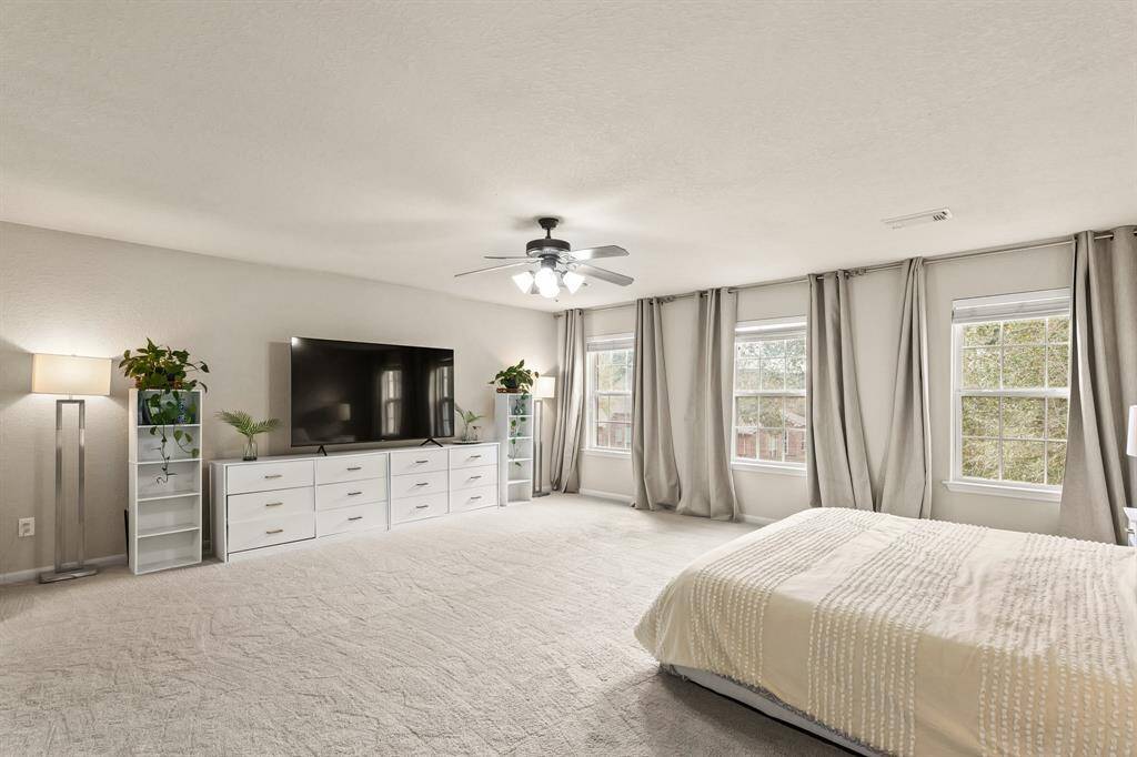 Unwind after a long day in this incredible Primary Bedroom! It features carpet floors, a ceiling fan, and large windows.