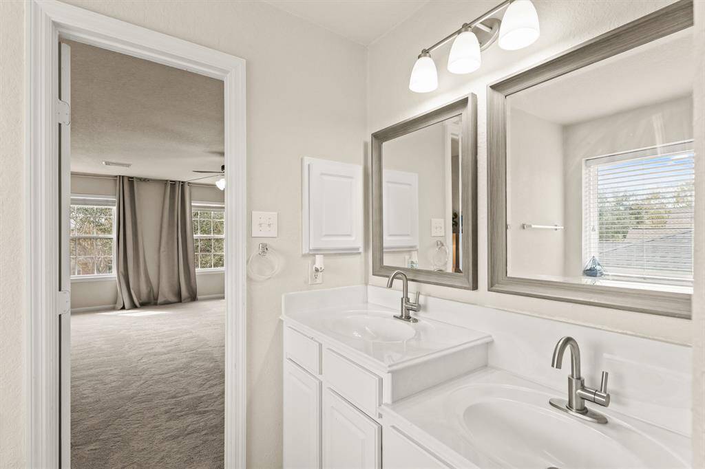 This bathroom includes double sinks, framed mirrors, and white cabinetry.