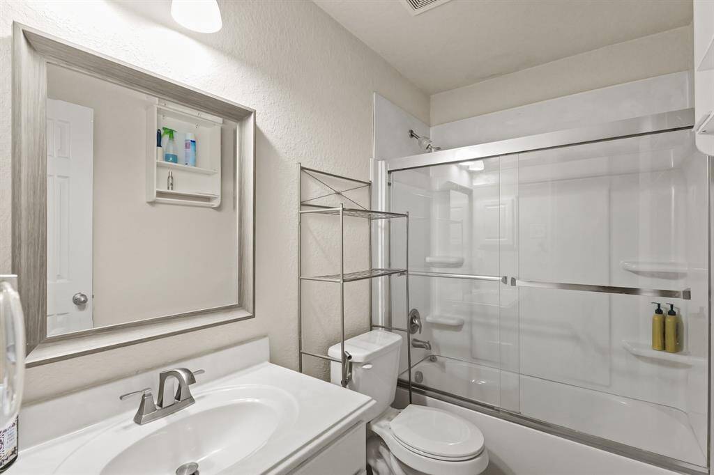 Secondary bathroom with quartz countertops and backsplash, framed mirror, and a shower/tub combo.