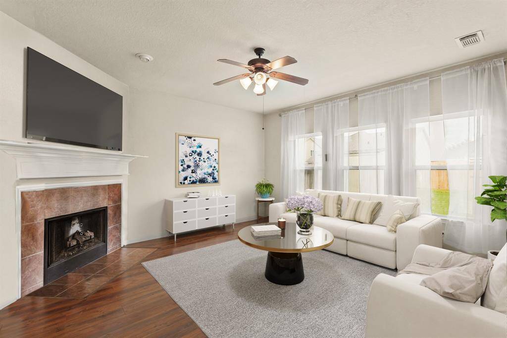 Virtually Staged: This stunning living room is open and bright. It is highlighted by a gorgeous fireplace with mantle, laminate floors, a ceiling fan, and large windows.