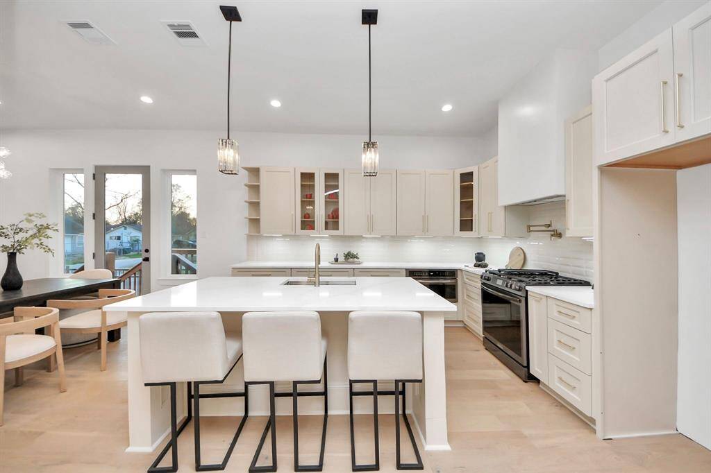 Under-cabinet lighting illuminates your countertop space, while the custom vent hood sits gracefully above gas range. The pot filler is perfectly positioned for convenience, eliminating the need to carry heavy pots to the sink.