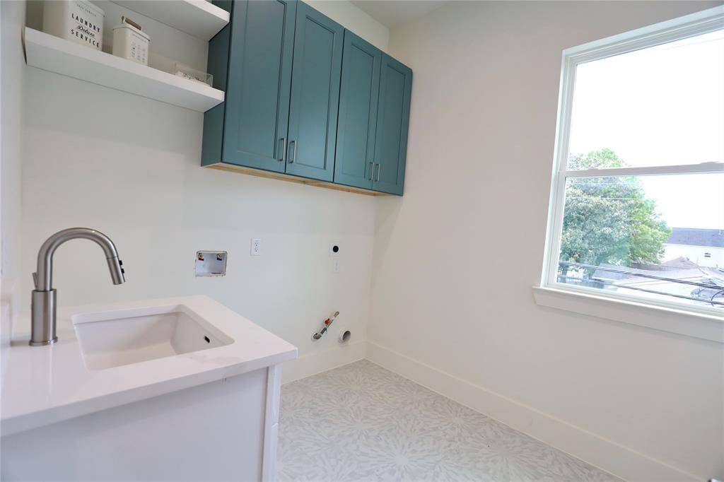 The spacious walk-in laundry room features a utility sink and a window that fills the space with natural light. The 24x48-inch tile flooring ensures easy cleanup, while gas connections for the dryer adding efficiency.