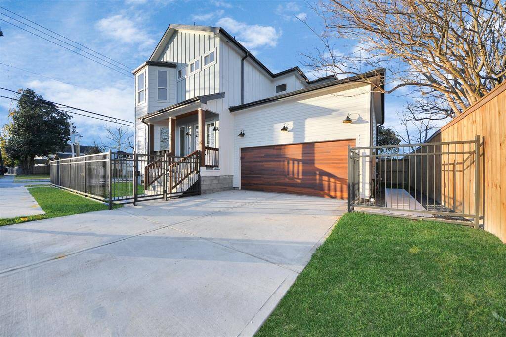 An expansive frontage home, redefining luxury in the area. The cedar-accented garage is beautifully illuminated by light fixtures and downlights, enhancing its curb appeal. The gutter system seamlessly aligns with the metal roof on the front porch and the home’s rounded window design.