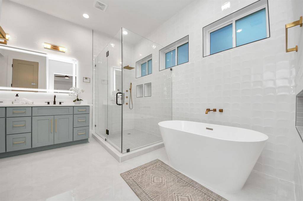 "The primary spa-like bath boasts 12-foot walls with individually installed wave tiles, creating a dynamic accent. Luxuriate in the rainfall showerhead, body sprayers, and handheld, while two convenient nooks provide easy access to your essentials.