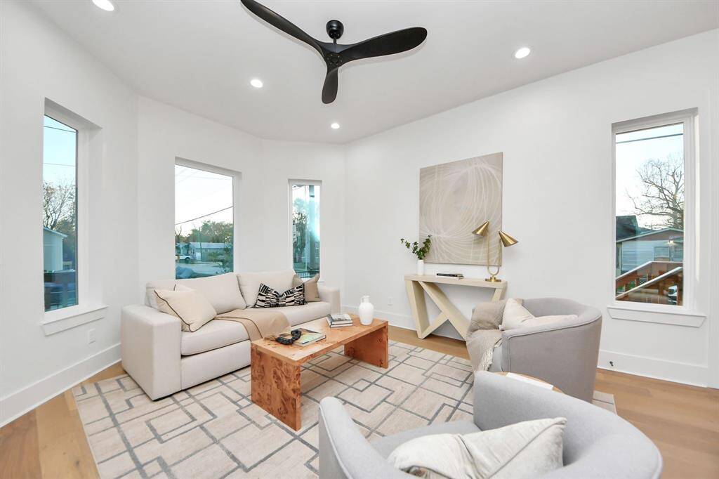 The living room's rounded windows flood the space with natural light, brightening the entire room. The fan adds both style and comfort to the atmosphere.